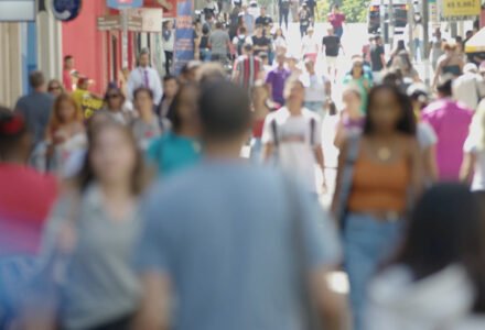 Pessoas caminhando em calçadão de área central urbana em Santa Catarina.