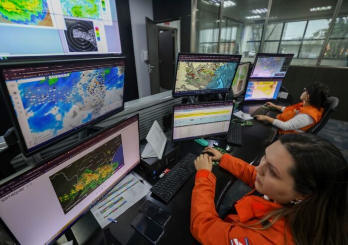 Técnico da Defesa Civil realizando monitoramento climático diante de telas de computador