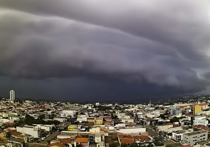 Ciclone extratropical se aproxima e provoca mudanças no tempo, com céu carregado sobre uma área urbana.